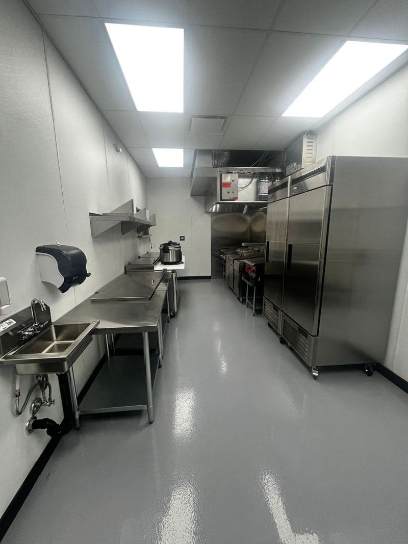 Commercial kitchen corridor with steel fridges and a clean floor
