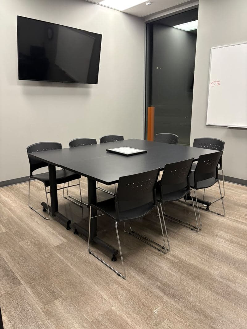 Meeting room with a dark table and chairs set out after an evening clean