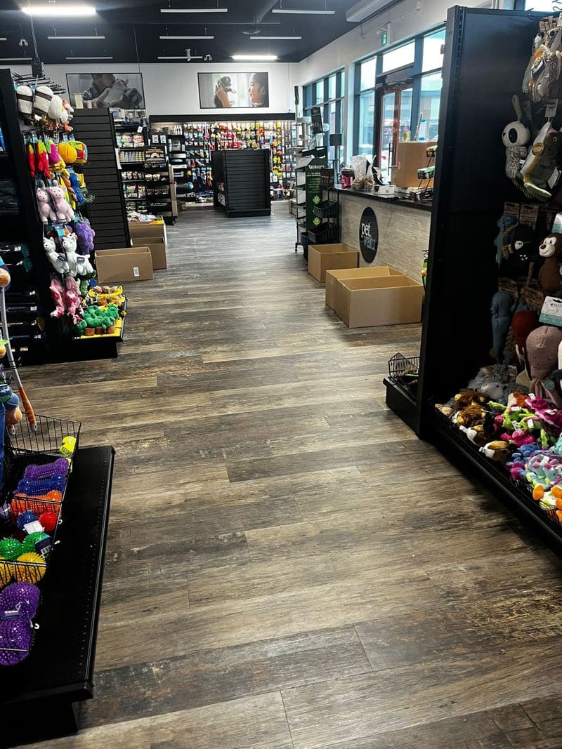 Pet store aisle with a clean wood-effect floor and stocked shelves