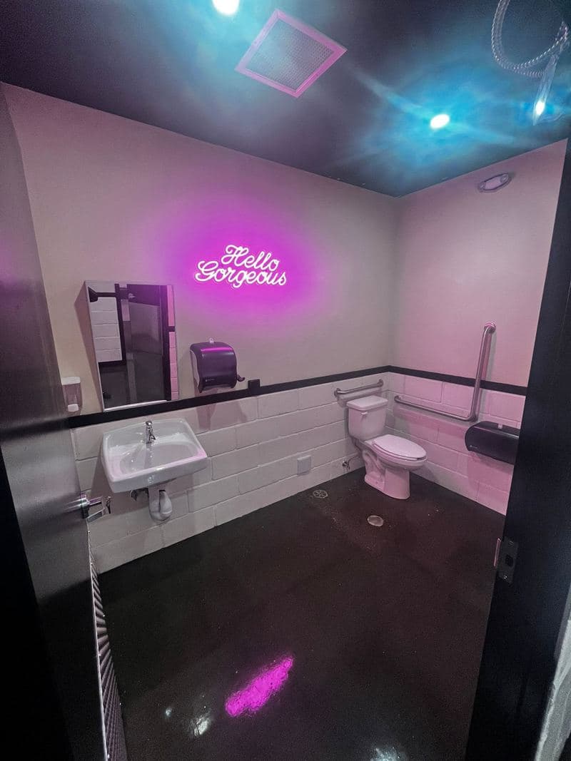 Salon washroom with a neon sign, clean basin and gleaming tiles