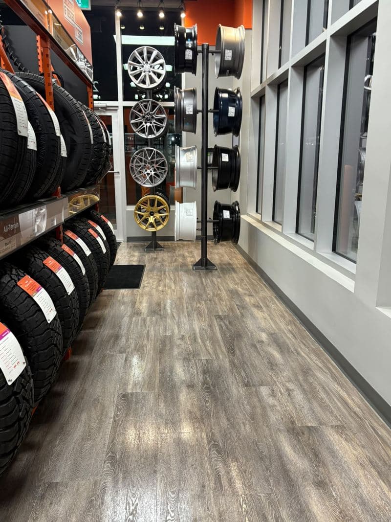 Tyre showroom aisle with a polished wood-effect floor and wheel displays